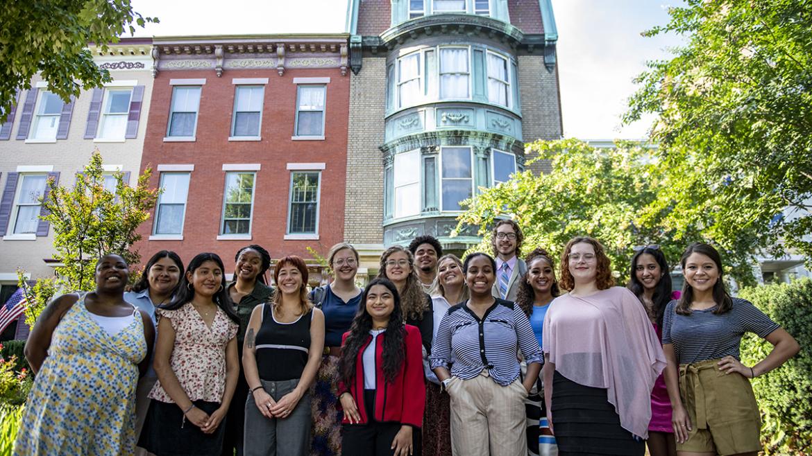 A group of diverse young adults from FCNL's 2022-2023 Advocacy Corps smile in front of Friends Place on Capitol Hill