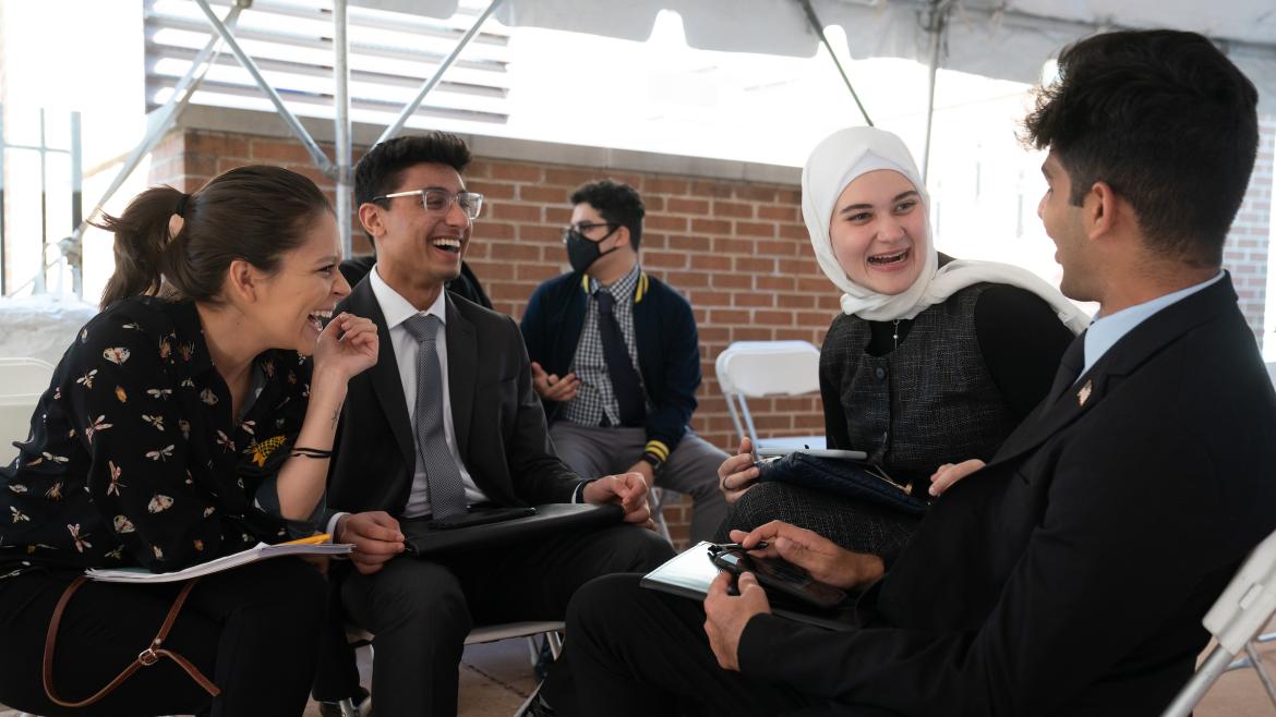 group of young adults laugh and converse on Quaker Welcome Center patio